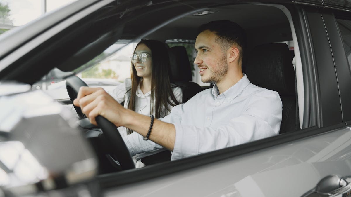A young couple smiling while driving together in a modern car interior.