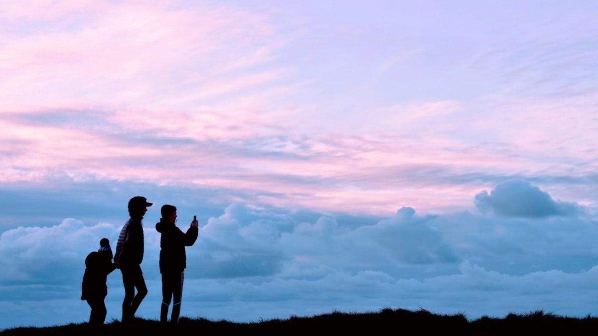 a group of people standing in front of a sunset